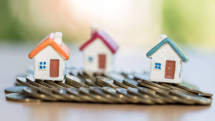 Finance & Investment Concept - A Wooden Kit of The Houses Placed Behind Coins.