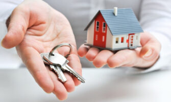 A Person Having A Homekit In One Hand A Key In Other Hand Representing Mortgage Loan Concept.