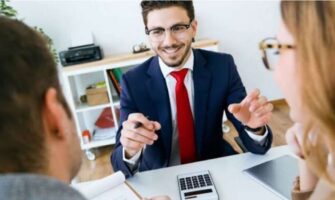 A Smiling Bank Employee Explaining About Loan Agreements To His Customers.