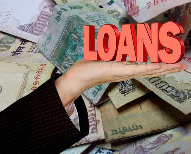 An image representing the term LOAN placed on a palm, on top of currencies