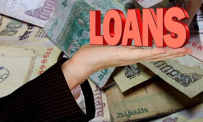 An image representing the term LOAN placed on a palm, on top of currencies